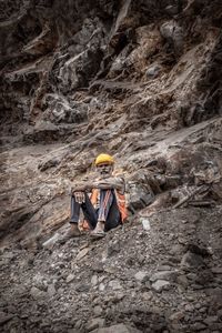 Low angle view of man sitting on rock formation