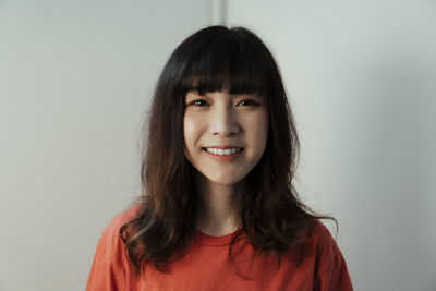 Portrait of smiling young woman against white background