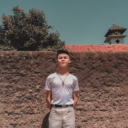 Portrait of young man standing against tree