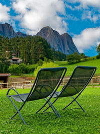 Chairs on grassy field against sky