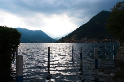 Wooden posts in lake against sky