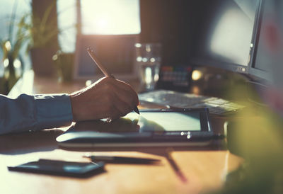 Cropped hand on businessman writing on graphics tablet