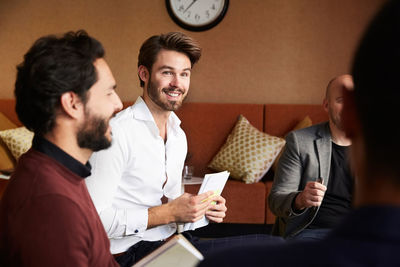 Male entrepreneurs discussing with coworkers while sitting at workplace