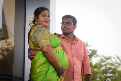 Portrait of smiling couple standing against sky