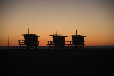 Lifeguard hut in sea against sky during sunset