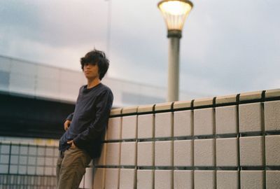 Man leaning on retaining wall during sunset