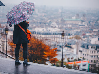 Rear view of man standing in city during rainy season