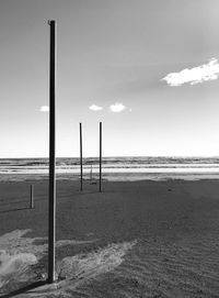 Wooden posts on beach against sky