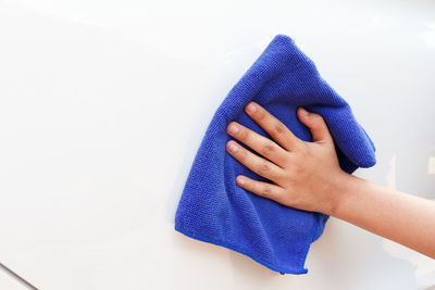 Close-up of woman hand holding purple paper against white wall