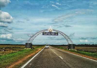 View of bridge over road against cloudy sky