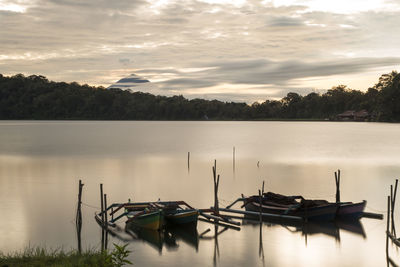 Sailboats moored in lake against sky during sunset