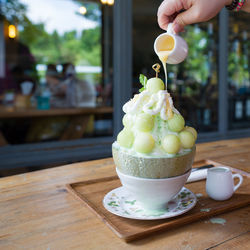 Midsection of person holding ice cream on table