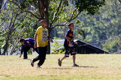 Full length of boy running on street amidst trees