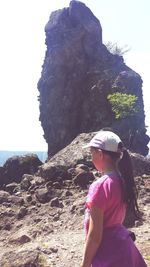 Rear view of woman standing on rock against sky