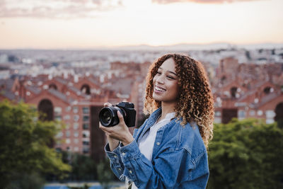 Portrait of smiling young woman standing against camera