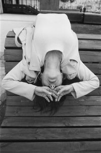 High angle view of woman lying on wooden seat