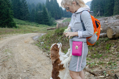 Woman and adorable cavalier king charles spaniel waiting to receive a sweet from her
