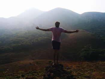 Rear view of man with arms outstretched standing on mountain