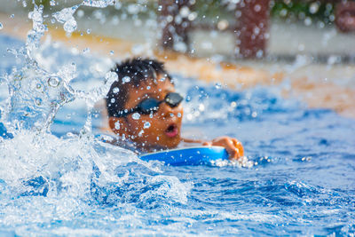 Close-up of boy splashing water in swimming pool