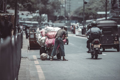 Rear view of people riding motorcycle on road