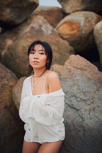 Portrait of sensuous young woman standing against rocks