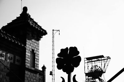 Low angle view of silhouette statue against building