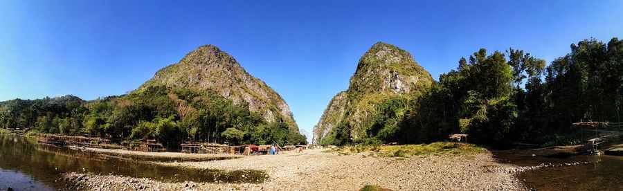 Panoramic shot of rocks and trees against clear blue sky