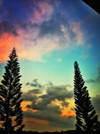 Low angle view of trees against cloudy sky