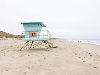 Blue lifeguard hut at beach against clear sky