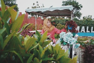 Portrait of smiling woman with flowers on plants