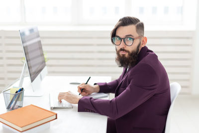 Young man using mobile phone while sitting on table