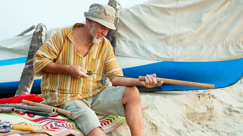 Midsection of man holding umbrella while sitting outdoors