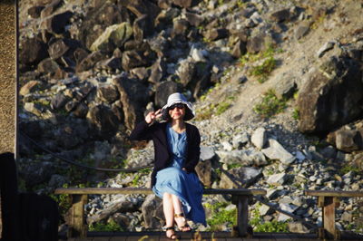 Full length of woman photographing while standing on rock