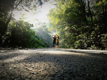 People on road amidst trees against sky