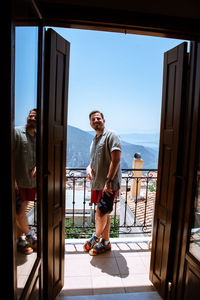 Portrait of a young man standing in the balcony near high rocky mountains