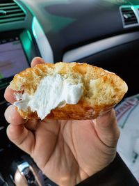 Midsection of person holding ice cream cone in car