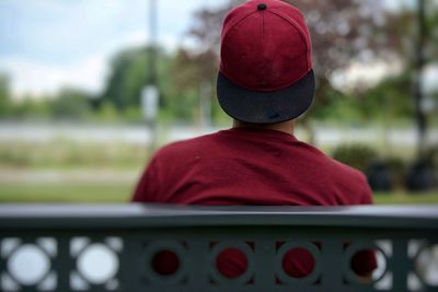 Rear view of boy wearing hat while sitting on bench