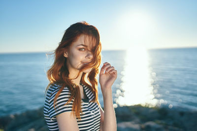 Portrait of beautiful young woman against sea