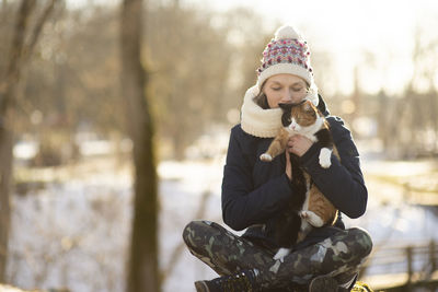Young woman holding cat and meditation in city park