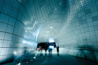 People walking in illuminated tunnel