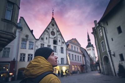 Man looking away while standing on street during sunset