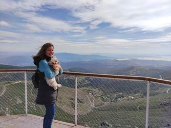 Full length of woman standing on railing against sky