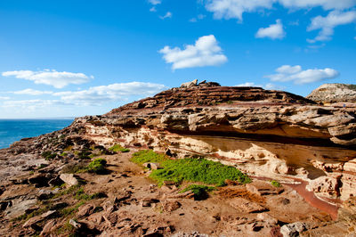 Scenic view of rocky mountain by sea against sky