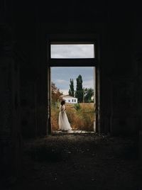 Rear view of woman looking through window