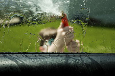 Boy washing car seen through window