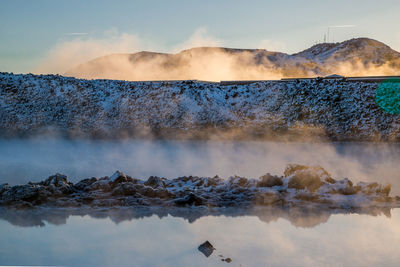 Steam emitting from volcanic landscape against sky