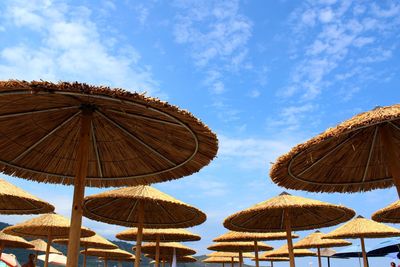 Low angle view of thatched roof parasols against sky