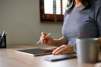 Midsection of woman using mobile phone on table