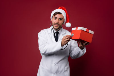 Portrait of young man standing against red background