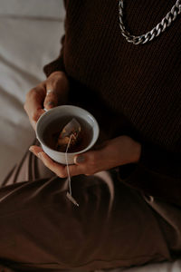 Midsection of woman holding coffee on table